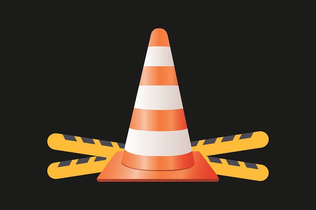 Under Construction image with yellow and black striped warning barriers and an orange and white traffic cone in front